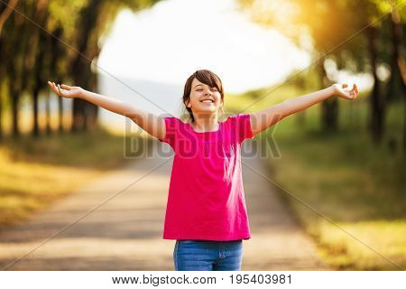 Beautiful little girl with her arms outstretched enjoys in nature.