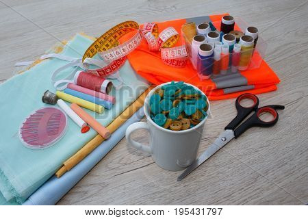 Sewing tools and sewing kit on wooden textured background. Sewing kit. Thread needles and cloth. tailor workspace with sewing and handmade tools