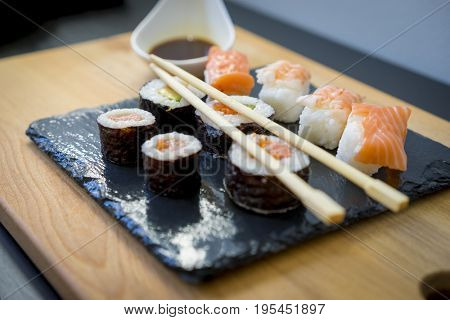Gourmet, Sushi on a wooden table on black slate plate with soy sauce and chopsticks