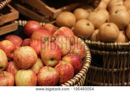 Apples in the basket lay beside Chinese pear in supermarket.