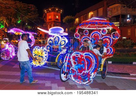 Melaka Malaysia - April 20 2017: Colourful trishaws decorated with bright multi-colour lights and cartoon pictures are ready to take passengers for sight-seeing the old town in night time.