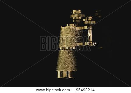 An old pair of binoculars on a dark background.