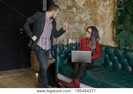 Handsome young bearded businessman having angry disappointed look showing index finger to his female secretary making remark complaining about something. People business and relationships