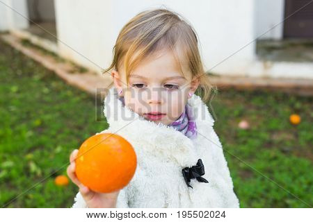 Cute baby girl showing orange in the garden