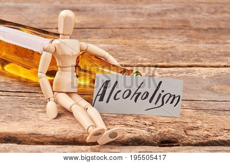 Human wooden dummy and alcohol. Alcoholism ruins the organism.