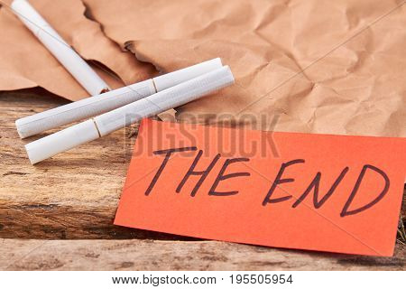 Cigarettes smoking leads to death. Text the end, cigarettes, old wooden background.