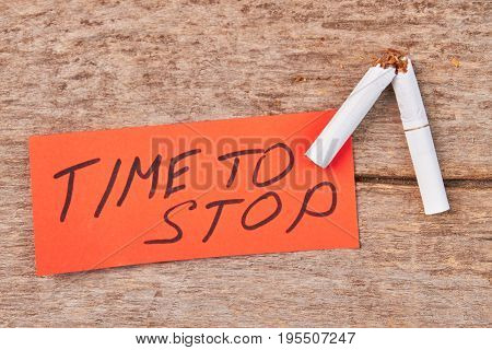 Broken cigarette, message, wooden background. Time to stop smoking cigarette concept.