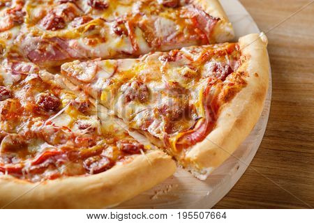 Fresh cooked pizza on wooden board. Close-up view of piece of pizza