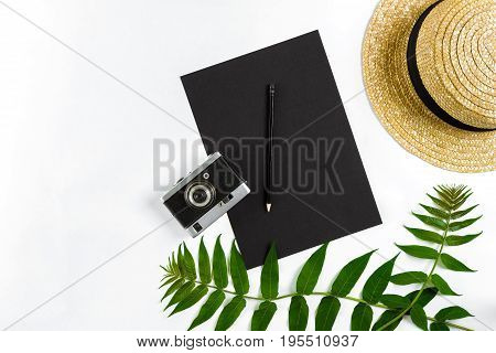 Straw hat with green leaves and old camera on white background, Summer background. Top view. Copy space. Still life. Flat lay