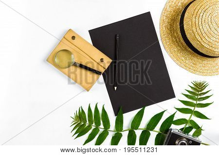 Straw hat with green leaves and old camera on white background, Summer background. Top view. Copy space. Still life. Flat lay