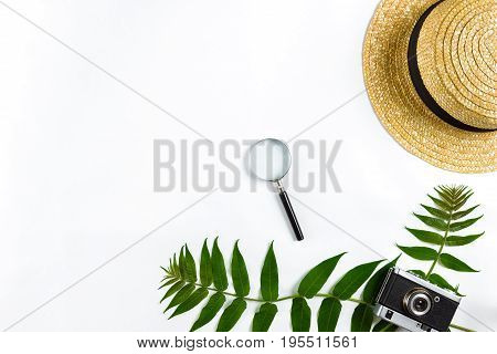 Straw hat with green leaves and old camera on white background, Summer background. Top view. Copy space. Still life. Flat lay