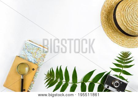 Straw hat with green leaves and old camera on white background, Summer background. Top view. Copy space. Still life. Flat lay