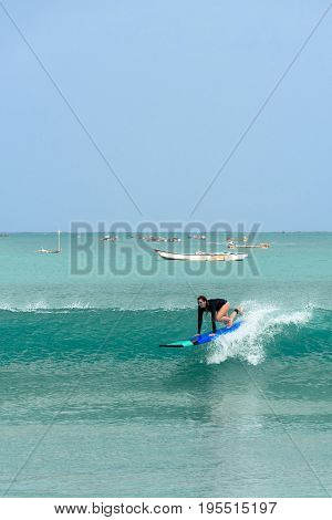 10/06/2017 Pantau Mawun Lombok Indonesia. Young woman learns to surf on a long board on learner waves in a paradise location.
