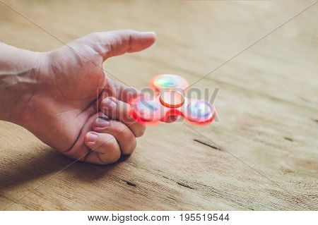A Man Hand Holding Hand Spinner Or Fidget Spinner Over Wooden Background