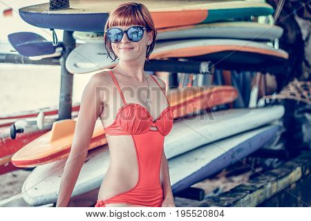 Young sexy girl in red swimsuit - surfer with surf board posing on the Nusa Dua beach, tropical Bali island. Family lifestyle, people water sport lessons and beach swimming activity on summer vacation.