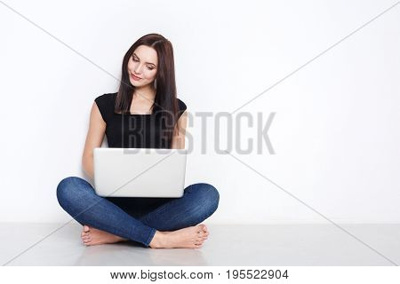 Freelance or work at home laptop. Beautiful woman in casual sit on floor and work with portable computer with crossed legs