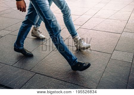 Legs in jeans of young man and woman in street shoes walking or going fast. Fast rhythm of life of modern city concept