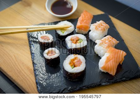 Asian food, Sushi on a wooden table on black slate plate with soy sauce and chopsticks