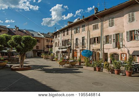 Conflans, France - June 29, 2016. Stone buildings and shops in the medieval village of Conflans near the town of Albertville. Mountains landscape and blue sky on background. France