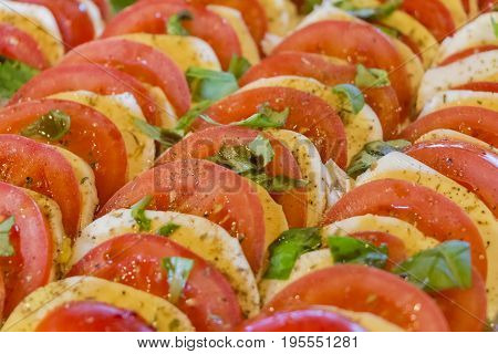 Delicious tomatoes and buffalo mozzarella chopped in salad row. Wonderful vegetarian vegan appetizer. Green bio and local food. Tomato and cheese in rows with herbs and basil. Healthy nutrition.