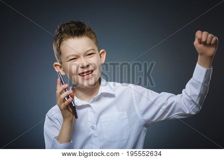 Closeup Portrait of happy boy with mobile or cell phone on gray background.