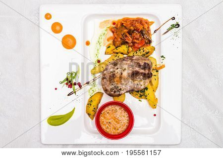 Top view bovine meat with potato and sauce decorated in white plate. Restaurant meal.