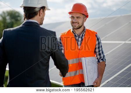 Foreman and businessman concluding a treaty. Agreement between two sides at solar energy station.
