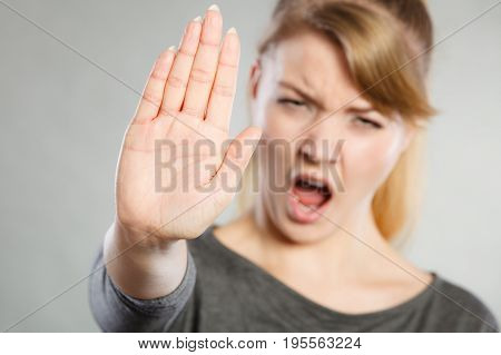 Prohibition symbol. Serious female shows stop sign talk to hand gesture. Angry full of negative emotions woman with hand palm stopping.