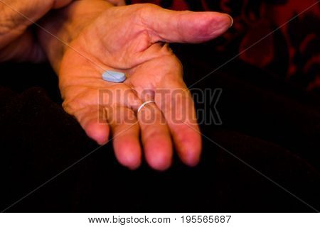 Hand of an older woman holding colored medicines