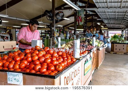 Clanton Alabama USA - June 17 2017: An employee at Durban Farms Market restocks tomatoes in the display case.