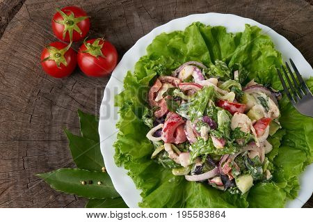 Fresh salad with fresh red cerry tomatoes cucumbers chicken red onion radish bell pepper lettuce with special spisy sauce on wooden table. Healthy eating and diet concept.