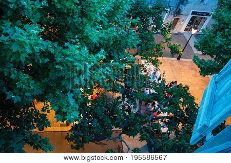 Rians, France - July 08, 2016. People in square restaurant with branches at the early evening, at the lovely village of Rians. Var department, Provence region, southeastern France.