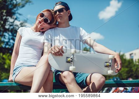 Young skater boy and girl with skateboard sitting on the street. Mock up.