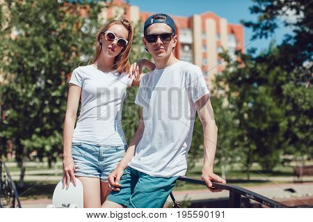 Young skater boy and girl with skateboard in white T-shirts on the street. Mock up.