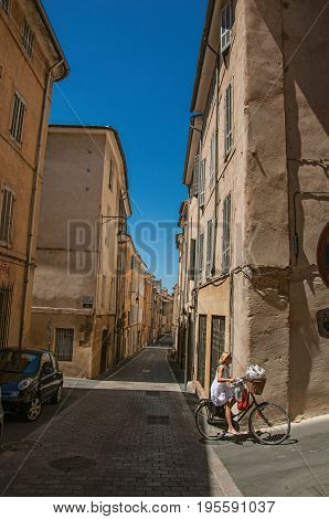 Aix-en-Provence, France - July 09, 2016. Woman riding bike in alleys of Aix-en-Provence, a pleasant and lively town in the French countryside. Provence region, southeastern France
