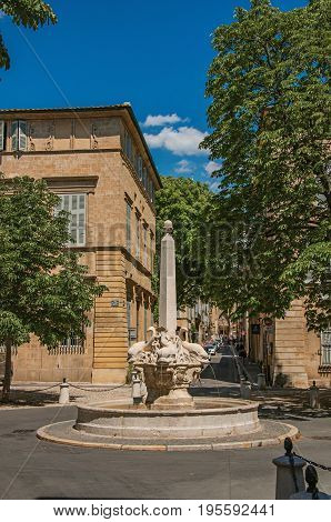 Aix-en-Provence, France - July 09, 2016. Street with buildings and fountain in sunny afternoon in Aix-en-Provence, a pleasant and lively town in the countryside. Provence region, southeastern France