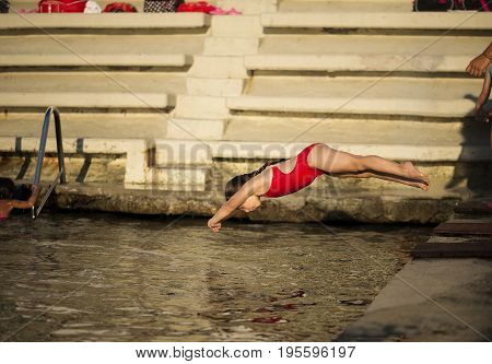 Little 6 years old caucasian girl jumping into the sea headlong leap of waters. Summer sport camp for junior divers first steps of future diving athletes.