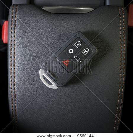 Wireless car key in modern car interior, black leather red stitch