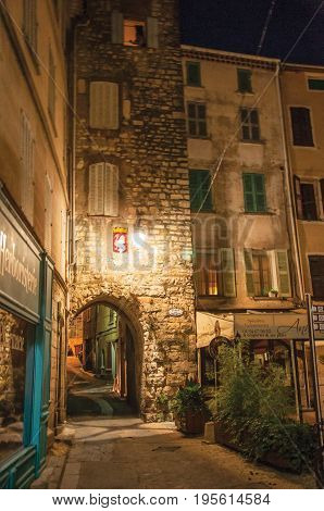 Draguignan, France - July 10, 2016. Night view of arch and square with buildings and light of lanterns, in the pleasant city of Draguignan. Provence region, Var department, southeastern France