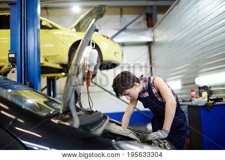 Female mechanic tuning one of cars in garage