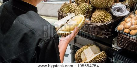 Woman hands holding durian with sharp thron shell after cutting. Peeling and packing service for sales in supermarket.