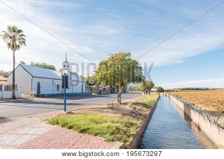 KEIMOES SOUTH AFRICA - JUNE 12 2017: The historic Dutch Reformed Mission Church in Keimoes now a museum an irrigation canal and vineyard next to the main road in Keimoes in the Northern Cape