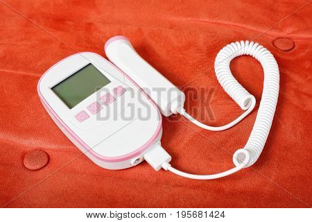 Medicine - Fetal Doppler on a red textile background