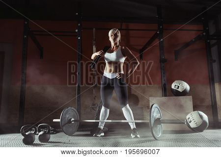 Beautiful sports blonde standing with ropes in the gym. Fitness woman in the gim.