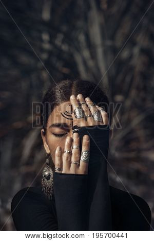 beautiful young woman in black dress cover half of face with hands
