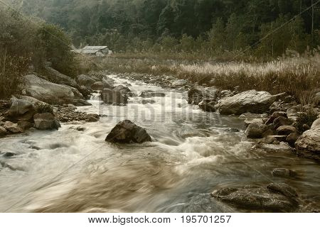 Beautiful Reshi River water flowing through stones and rocks at dawn Sikkim India. Reshi is one of the most famous rivers of Sikkim flowing through the state and serving water to many local people. Tinted image.