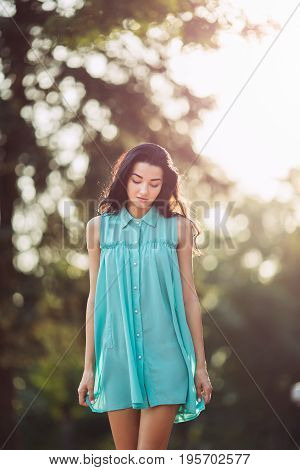 Charming young woman with long hair in dress blurred nature background. Attractive young multi-racial Asian Caucasian gorgeous girl model walking outdoors
