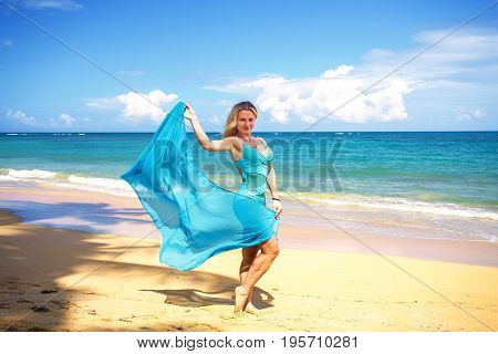 Young beautiful girl with blue pareo on tropical beach