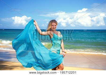 Young beautiful girl with blue pareo on tropical beach