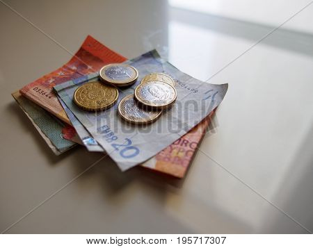 June 19 2017. Close-up macro detail of multiple euro bills and coins stacked on top of each other on a white reflective surface. Valencia Spain. European finance and economy editorial concept.